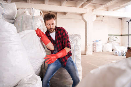 Man throwing over the shoulder heavy garbage bagの写真素材