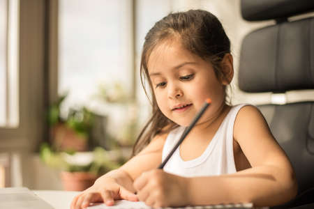 School girl studying online from home and making notes