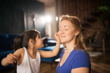 Girl playing her mother and touching her face, while she is meditating