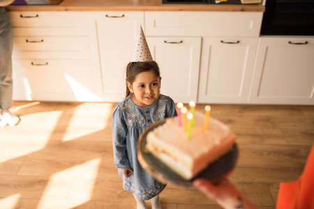 Girl looking at her birthday cake while preparing to blowing out the candlesの写真素材