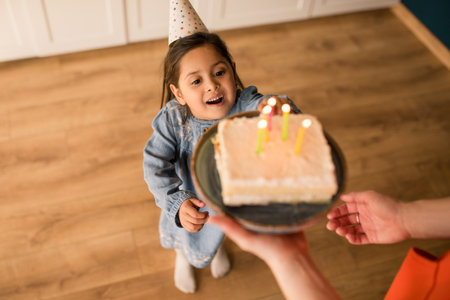 Girl wearing party cap blowing out the candles at her birthday cakeの写真素材