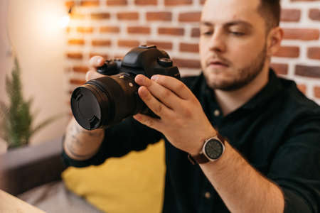 Man checking settings at his camera before the shooting at his own studioの写真素材