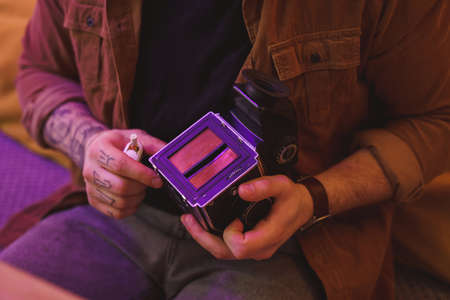 Man holding film camera and checking settings on it before the film developmentの写真素材