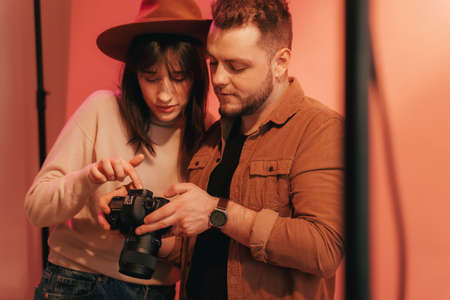 Photographer showing photos to his model and monitoring her reaction