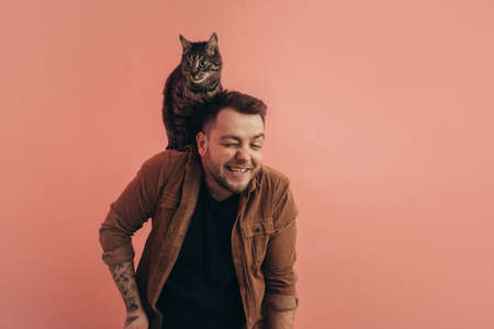 Man laughing while his striped cat sitting at his shoulderの写真素材
