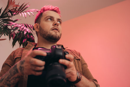 Photographer with digital photo camera at his hands posing in photo studioの写真素材