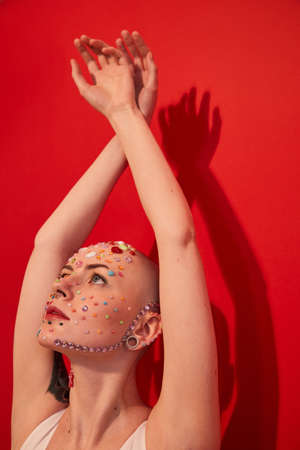 Masculine woman with decor at her face looking at her hands while keeping it over her headの写真素材