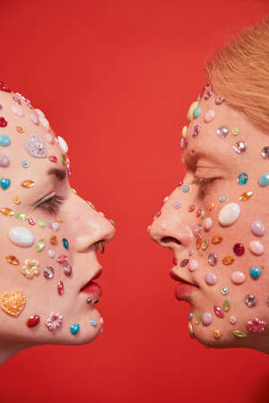 Mannish bald woman looking at the albino feminine man over the red background