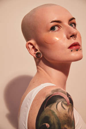 Bald unladylike woman with patches under her eyes posing with serious emotionsの写真素材