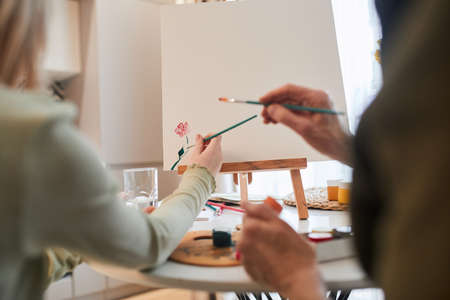 Kid drawing with paints while her grandmother sitting nearの写真素材