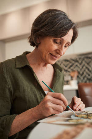 Woman looking at the picture and drawing while spending time at the kitchen