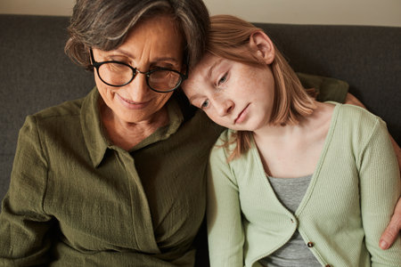 Girl bonding to her senior grandmother and watching something at the laptop