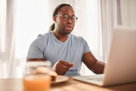 Unshaven man attentively looking at the laptop screen while having video call