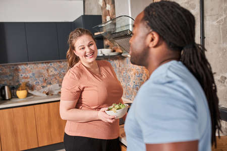 Woman looking at her husband and telling something while holding salad