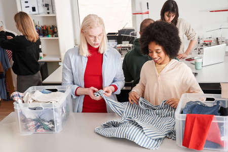 Woman and man putting clothes into the plastic container while sortingの写真素材