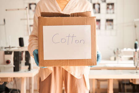 Woman working at the clothes sorting place and holding cupboard boxの写真素材