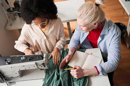 Designer drawing new sketches and telling something to his multiracial colleague