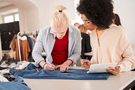 Woman looking attentively at the sketch drawing by her albino colleague
