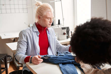 Man wearing glasses examining jeans and thinking how to re sewing it