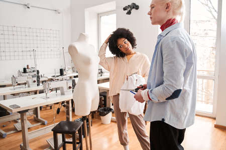 Colleagues standing in front of the mannequin and discussing re sewing processの写真素材