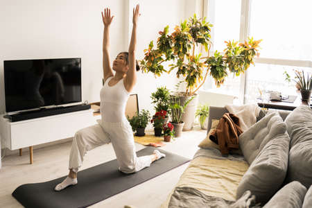 Asian woman stretching while standing on the mat