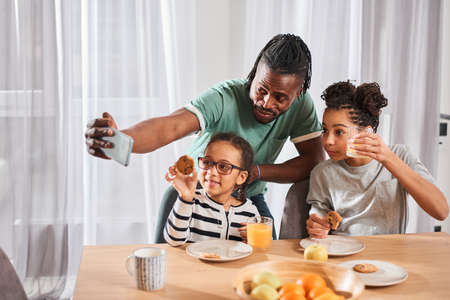 Family sitting at the table during the breakfast and making selfie