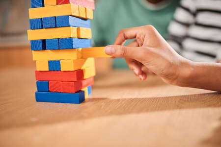 Girl pulls a bar while playing at the jenga with her father and sister