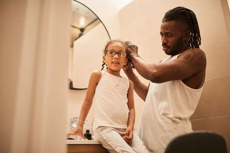 Multiracial man with dreadlocks doing hairstyle for his little daughterの写真素材