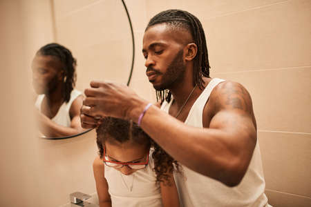 Cheerful father is making hairdo to his little loving daughterの写真素材