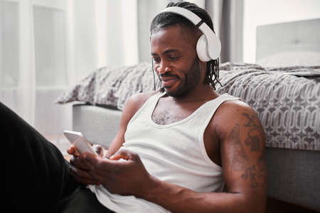 Man wearing headphones sitting at the floor and listening his favorite songsの写真素材