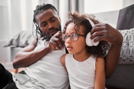 Father putting headphones on the head of his daughterの写真素材