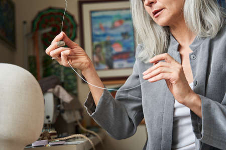Woman ends the handmade hat production, while holding wire for the shape of the hatの写真素材