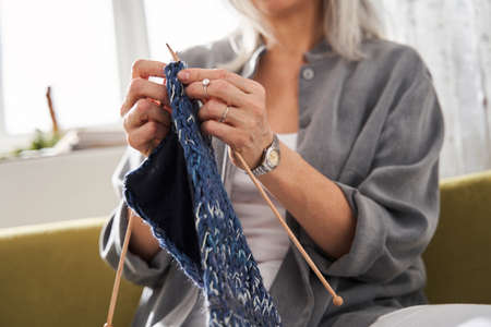 Knitting woman while enjoying knit work on the sofa at home