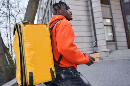 Multiracial man holding parcel cardboard box while going to the door entrance