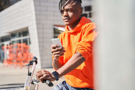 Courier guy checking order via mobile phone while standing on cityの写真素材
