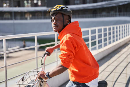 Male courier wearing helmet walking with bicycle on the city streetの写真素材