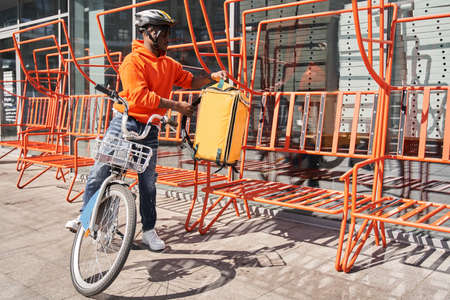Man courier taking his backpack with orders while going to the delivery addressの写真素材