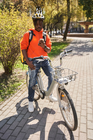 Guy wearing helmet checking order via mobile phone