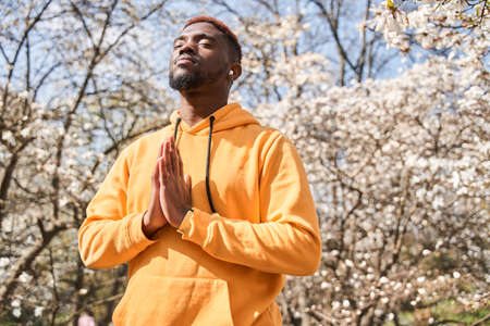 Man making praying gesture while standing in yoga position at the park