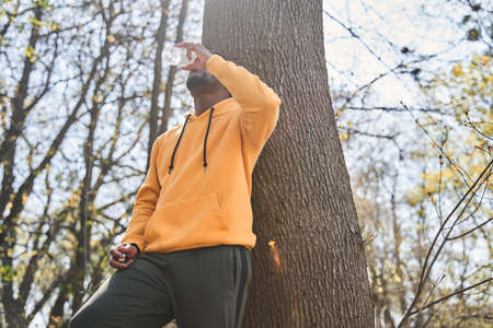 Man taking a break after serious training and greedily drinking water from the bottle