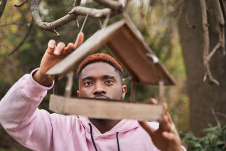Man keeping at the tree birds feeder and preparing to the feeding birdsの写真素材