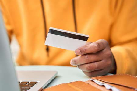 Man holding credit card while undergoing payment in internet in front of the laptopの写真素材