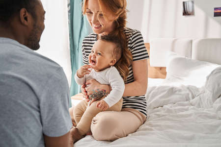 Family having fun with their kid on the bed while playing