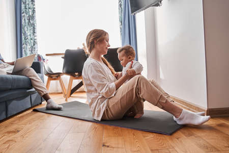 Woman meditating at home in the morning and practicing yoga while sitting at the floorの写真素材