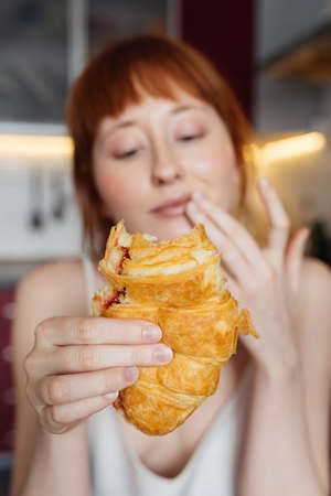 Woman enjoying breakfast while eating croissant with jam at the morningの写真素材