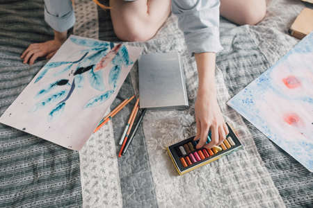 Woman reaching to the crayons while painting at the bedの写真素材