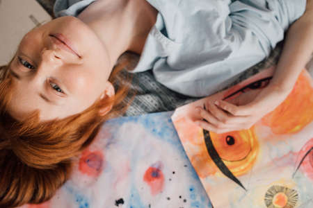 Girl posing around her pictures and smiling while laying at the bedの写真素材