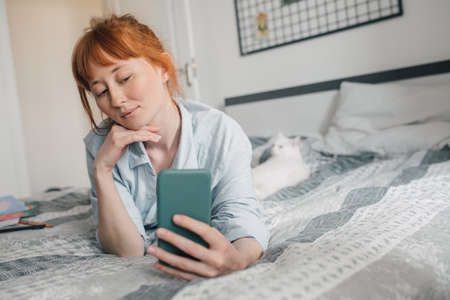 Girl spending her time at the bedroom with gadgetsの写真素材