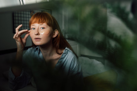 Woman with eye patches looking at the mirror while relaxing at the self isolation