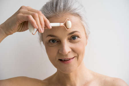 Woman looking at the camera and smiling while massaging her forehead